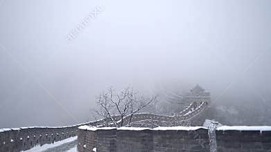 Fog is swooping on the low walls of the great wall of China during a freezing da
