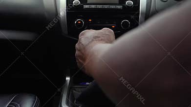 The male driver is changing the manual gear inside the car cabin.