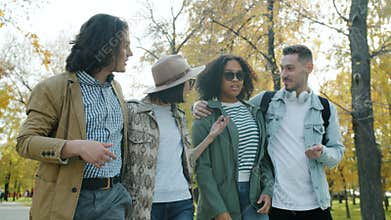 Happy young couples walking outdoors in park on sunny autumn day talking