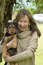 Smiling happy senior woman case of puppy love holding baby dog