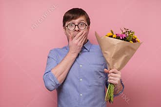 Young caucasian man in glasses having surprised face with flowers for his girlfriend