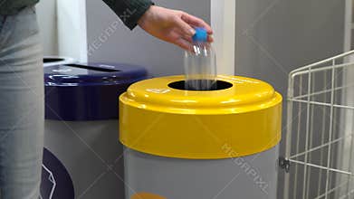 A young woman throws a plastic bottle into the trash. Special containers for sorting garbage. Container for plastic