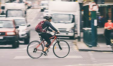 Woman biker commuting on bicycle in busy city street