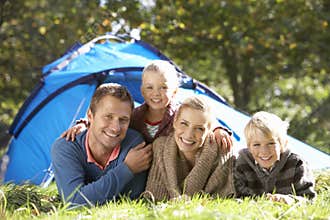 Young family poses outside of tent