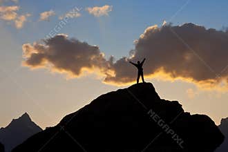 Man on the top of a cliff at sunset