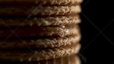Extreme close up view on traditional Dutch and Holland stroopwafels rotate or spin on a black mirror on a black