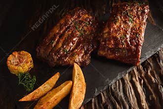 Food background of BBQ barbeque pork ribs served with potato fried and baked corn, selective focus