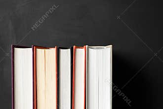 Stack of books on black cardboard background with copy space. Home education, learning and studying. Back to school