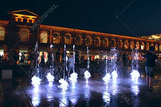 Children play with night fountains in the city of Lodz. Beautiful evening