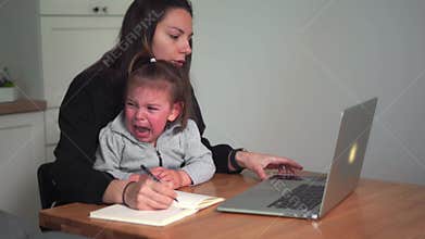 Stressed young woman working from home with small child. Home office of single mother