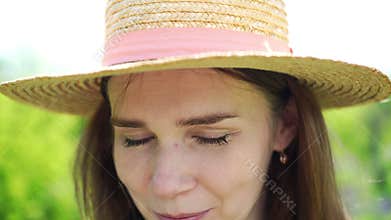 Woman in hat, tears streaming from his eyes due to sun and allergies.