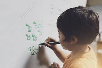 Portrait school kid drawing cartoon tank on white board, Child boy holding colour pen write on board, Education concept