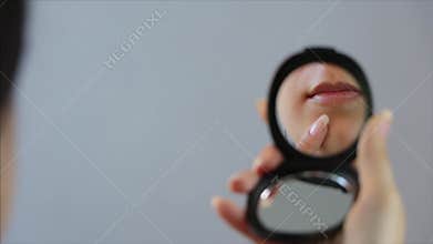 A woman applies concealer to a pimple on her face in the mirror. Close up. Acne, redness, blemishes, blackheads. Skin care, cosmet