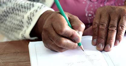 Older lady writing with a pencil in notebook