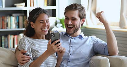 Overjoyed young couple looking at smartphone winning gift or prize