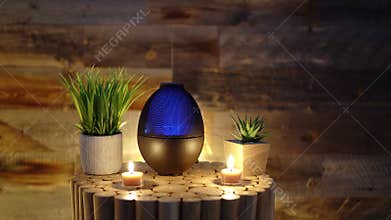 Aroma electric oil diffuser lamp, candles on wooden table in room. Aromatherapy, 4k