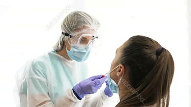Nurse in a protective suit takes a nasal swab sample from a young patient. COVID-19.
