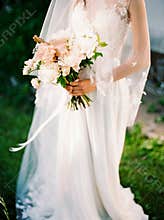 Bridal bouquet close up in hands of the bride outdoor, soft background. Modern beautiful bride with peach wedding bouquet. White l