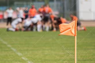 Flag on the pitch with rugby match in background