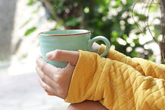 Young woman holding cup of morning coffee or tea in hands outdoors. Still life, self love and care concept.