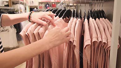Close up hands of woman choosing t-shirt clothes in department store