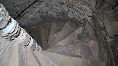 Descending the spiral staircase to the dungeon. Ancient stone staircase in the tower
