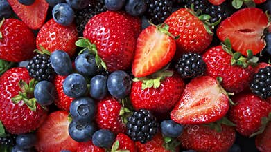 Wild forest berries on black background, collection of strawberry, blueberry and blackberry.