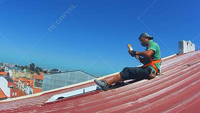 Roof repairing job - male roof worker on a red corrugated rooftop