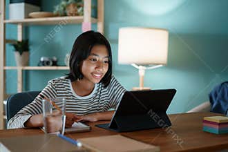 Homeschooling Asian girl doing homework And study online with tutor on tablet at desk at night