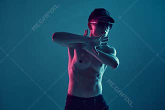 Cool young guy breakdancer in sunglasses and cap dancing hip-hop without shirt in neon blue light. Dance school poster