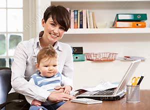 Woman With Baby Working From Home Using Laptop