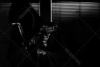 Burglary and robbery. skillful professional masked burglar holding a gun and crowbar and breaking into the house, hand close up on