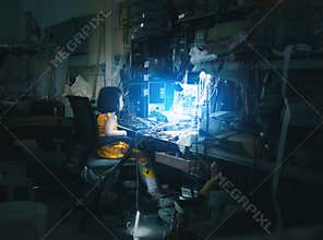 Little girl sitting in front of blue screen monitor as technical routine in computer and phone repair shop service with messy offi