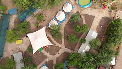 Aerial top view shot of the luxury camping with big white tents and marquees, Stylized territory, trails and camp