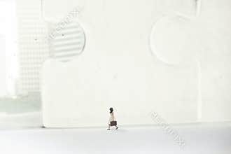 Business woman walking in a surreal city of skyscrapers and giant puzzles