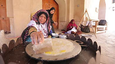 Arabic woman in traditional dress prepares a tortilla with filling.