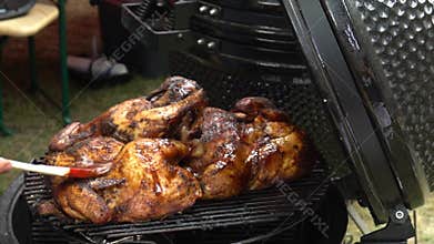 Chef hands paint whole chicken with spice brush on grill. Slow motion shot