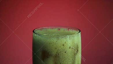 Pouring soft drink in glass with ice splash on red background. Cola or refreshment.