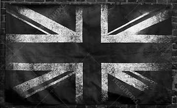 Monochrome image of an old stained dirty union jack british flag with dark crumpled edges on a brick wall background