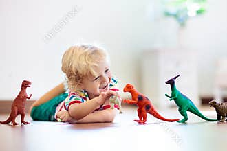 Child playing with toy dinosaurs. Kids toys