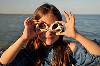 Summer fun concept with portrait of a girl with shells on a beach