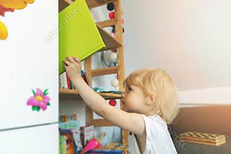 Child takes book from bookshelf