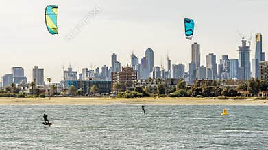 Pair of kitesurfers trains in Port Phillip Bay, with the skyline of Melbourne, Australia in the background