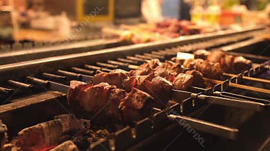 Appetizing delicious fried pieces of meat on skewers are roasted on a large grill in the open air. The chef prepares a barbecue.