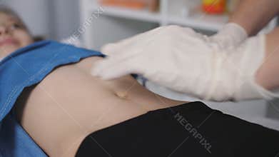 The doctor palpated the abdomen of a young patient in a medical office., close-up.