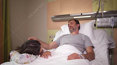 Male patting beloved wife asleep at his bedside
