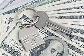Home keys and a small house on currencies dollar background