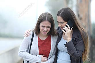 Girl suffering belly ache and a friend calling assistance