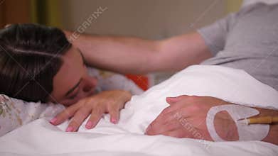 Sick man stroking sleeping wife in clinic
