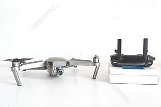 Drone and remote control next to some books in a drone pilot classroom against a white background. No people